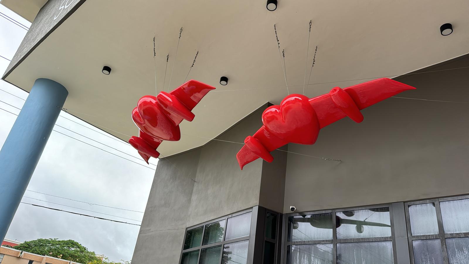 Close-up daytime view of the two winged-heart sculptures suspended beneath the building's entrance overhang.