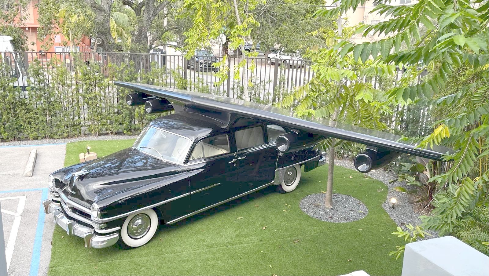 Elevated view of the completed sculpture on artificial turf in a courtyard, framed by trees and greenery.