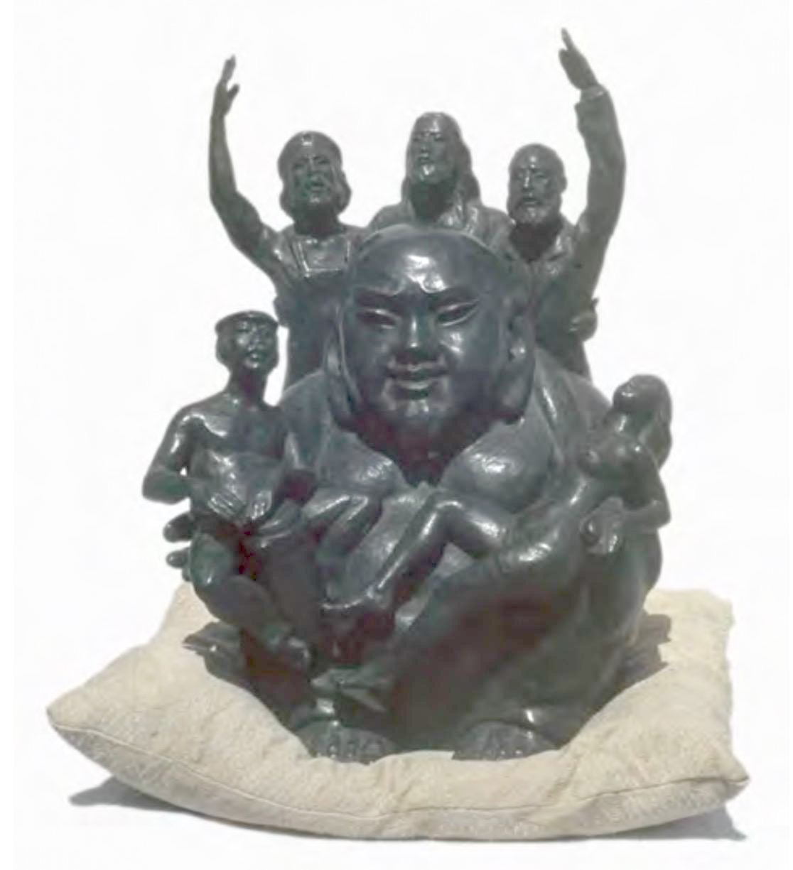 Bronze sculpture of a large, smiling bald figure seated cross-legged on a cushion, cradling several small nude figures against its belly while three more figures stand behind with arms raised overhead.